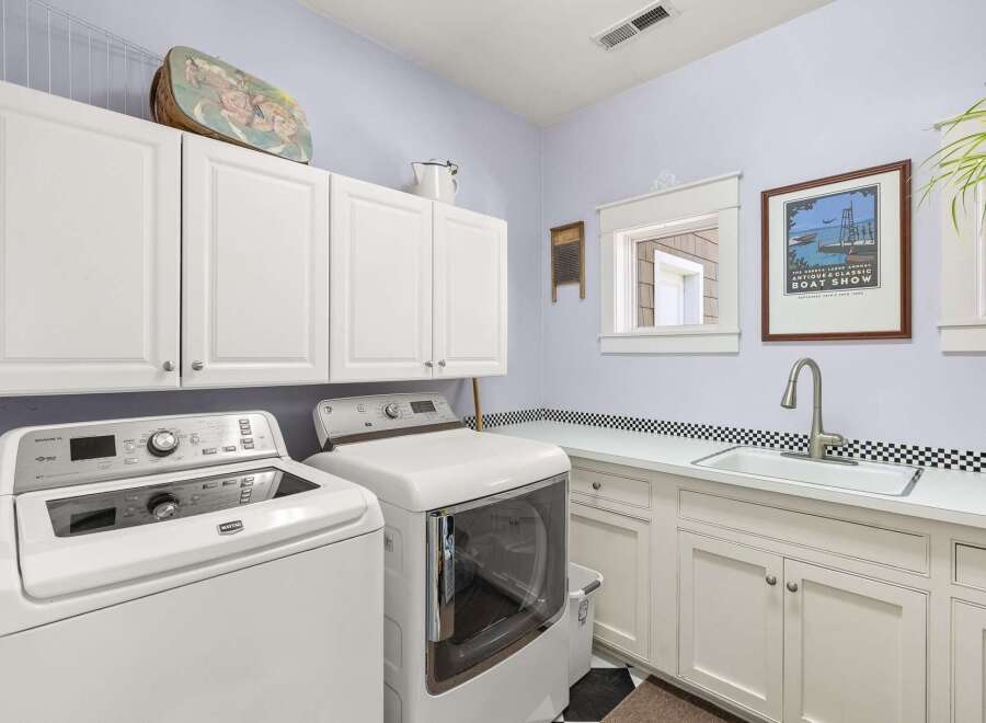 This spacious laundry room features a Maytag washer and dryer set, complemented by ample white cabinetry for storage.