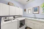 This spacious laundry room features a Maytag washer and dryer set, complemented by ample white cabinetry for storage.
