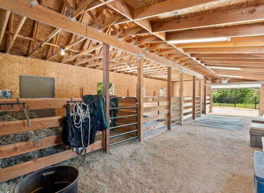 Discover this charming equestrian facility featuring multiple horse stalls with sturdy wooden fencing and convenient metal gates.