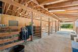 Discover this charming equestrian facility featuring multiple horse stalls with sturdy wooden fencing and convenient metal gates.