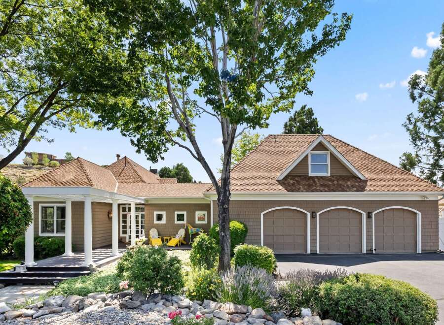 This charming home features a welcoming covered porch with white columns, leading to a spacious interior.