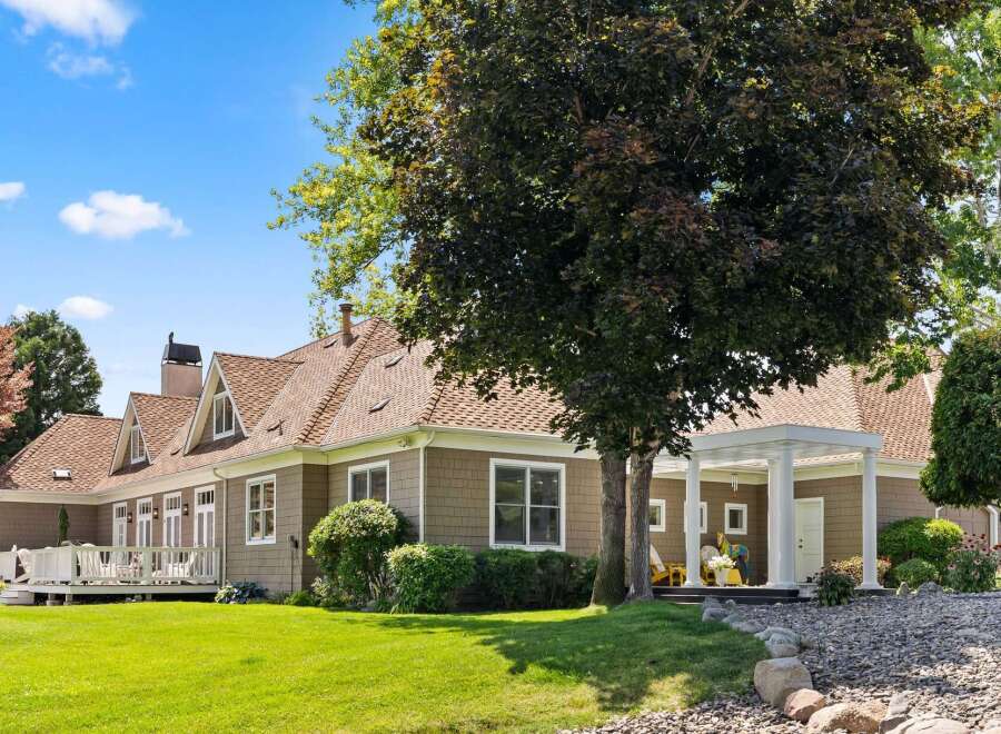 This charming home features a spacious wrap-around deck perfect for outdoor entertaining, complemented by a covered porch with elegant columns.