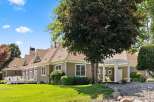 This charming home features a spacious wrap-around deck perfect for outdoor entertaining, complemented by a covered porch with elegant columns.