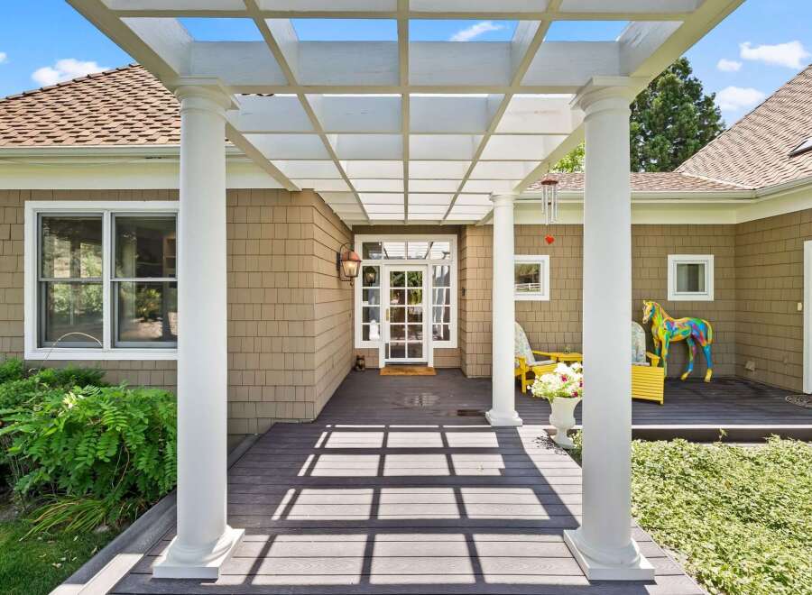 Welcome guests to this charming home with a covered front porch featuring a white pergola and elegant columns.