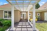 Welcome guests to this charming home with a covered front porch featuring a white pergola and elegant columns.