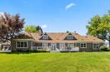 This expansive home features a charming brown exterior with a classic brown shingle roof, complemented by a spacious white deck perfect for outdoor entertaining.