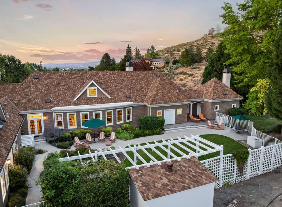 Experience luxury living in this stunning home, featuring a spacious backyard with a white pergola and ample seating areas perfect for entertaining.