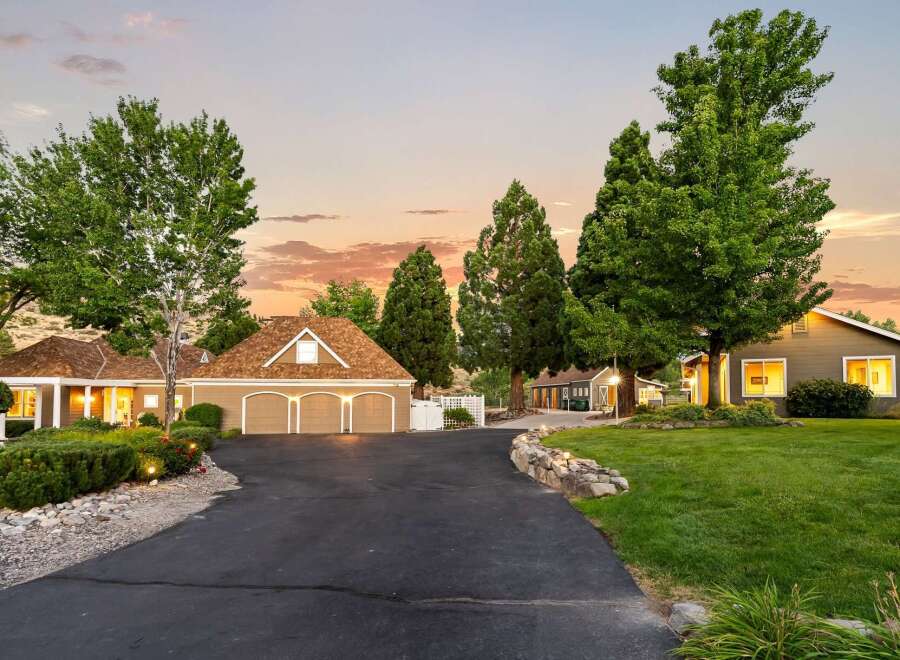 Discover this stunning property featuring a spacious three-car garage and a charming main residence, both with attractive brown roofs.