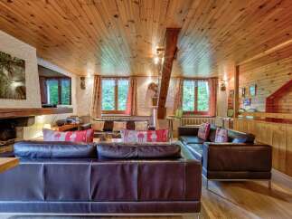 Experience rustic charm in this inviting living room, featuring a grand stone fireplace and a warm, wood-paneled ceiling.