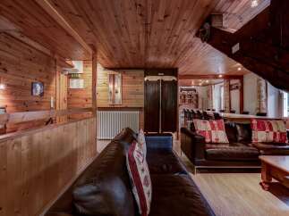Experience rustic charm in this beautifully appointed living space, featuring rich wood paneling throughout and comfortable leather seating.
