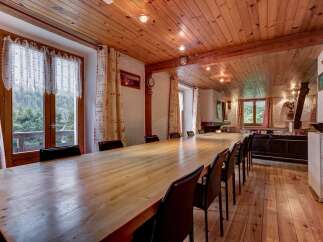 Experience rustic charm in this spacious dining room, featuring a long, polished wooden table perfect for gatherings.