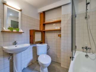 This charming bathroom features a pedestal sink with a mirror and a built-in medicine cabinet.