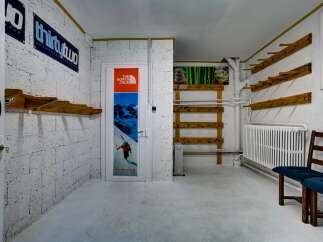Discover a unique space with ample storage for your winter gear, featuring multiple wooden racks perfect for skis or snowboards.