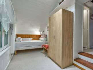 Discover this charming attic bedroom, featuring a comfortable single bed with a wooden headboard and a rolled-up duvet.