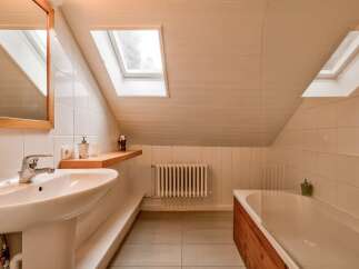 This charming bathroom features a spacious bathtub with a wooden surround, perfect for relaxing soaks.