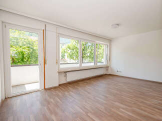 Bright and airy living space featuring a large balcony door and expansive windows that flood the room with natural light.