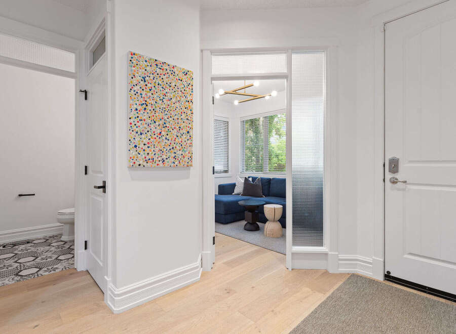 Step into a welcoming entryway featuring a vibrant abstract art piece and a glimpse into a stylish living area with a deep blue sofa.