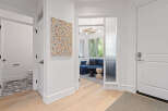 Step into a welcoming entryway featuring a vibrant abstract art piece and a glimpse into a stylish living area with a deep blue sofa.