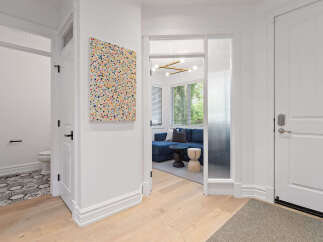Step into a welcoming entryway featuring a vibrant abstract art piece and a glimpse into a stylish living area with a deep blue sofa.