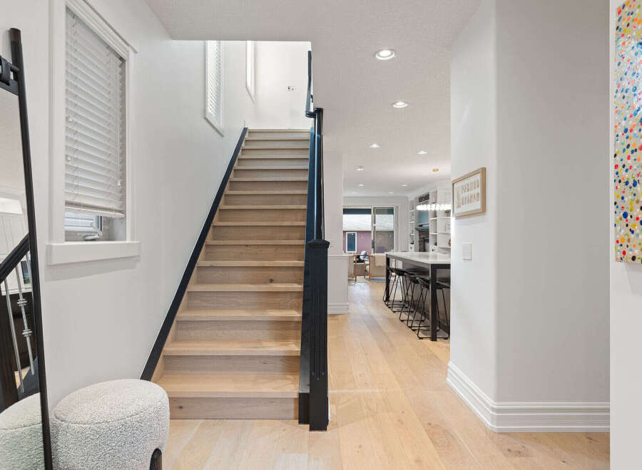 Step into this stunning home featuring a modern staircase with light wood treads and a sleek black railing.