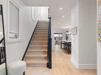 Step into this stunning home featuring a modern staircase with light wood treads and a sleek black railing.