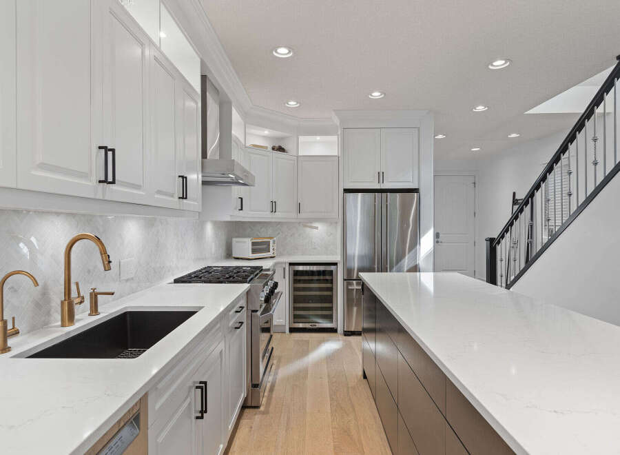 Experience modern luxury in this stunning kitchen, featuring sleek white cabinetry, a striking marble backsplash, and elegant gold fixtures.
