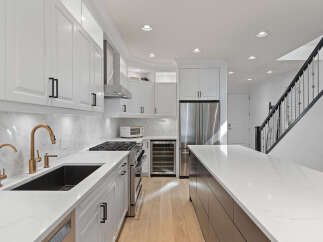 Experience modern luxury in this stunning kitchen, featuring sleek white cabinetry, a striking marble backsplash, and elegant gold fixtures.