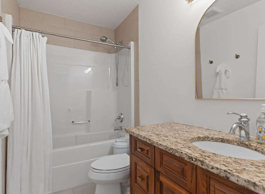 This inviting bathroom features a pristine white bathtub and shower combination, complemented by a sleek chrome showerhead and faucet.
