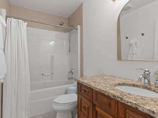 This inviting bathroom features a pristine white bathtub and shower combination, complemented by a sleek chrome showerhead and faucet.