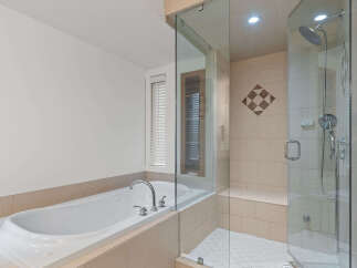 Indulge in luxury with this stunning bathroom featuring a deep soaking tub perfect for relaxation and a spacious, modern glass-enclosed shower.