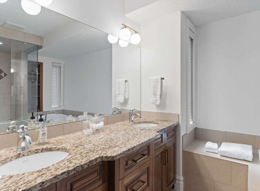 Experience luxury in this spacious bathroom featuring a double vanity with granite countertops and elegant wooden cabinetry.