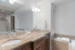 Experience luxury in this spacious bathroom featuring a double vanity with granite countertops and elegant wooden cabinetry.
