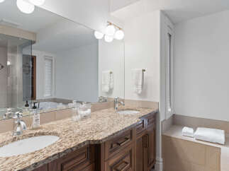 Experience luxury in this spacious bathroom featuring a double vanity with granite countertops and elegant wooden cabinetry.