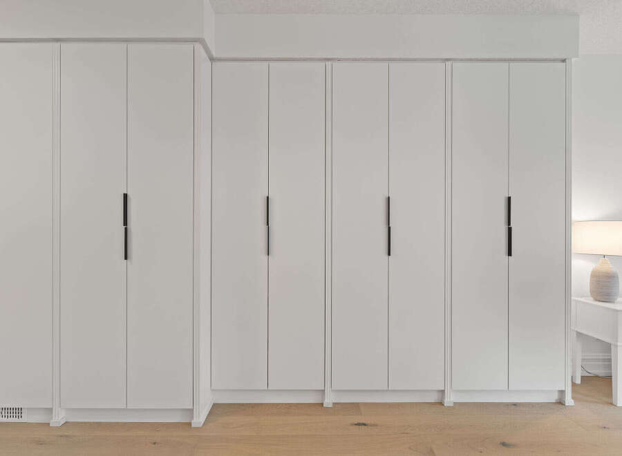 Experience seamless storage with this modern built-in wardrobe featuring sleek, minimalist doors and integrated black handles.
