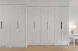 Experience seamless storage with this modern built-in wardrobe featuring sleek, minimalist doors and integrated black handles.