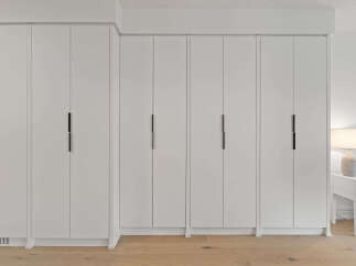 Experience seamless storage with this modern built-in wardrobe featuring sleek, minimalist doors and integrated black handles.