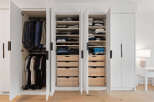 Discover organized living with this spacious walk-in closet, featuring ample hanging space for suits and shirts, complemented by multiple shelves and drawers for folded clothes and accessories.