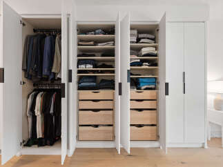 Discover organized living with this spacious walk-in closet, featuring ample hanging space for suits and shirts, complemented by multiple shelves and drawers for folded clothes and accessories.