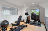 Elevate your fitness routine in this dedicated home gym, featuring a versatile weight bench, a Peloton bike, and a comprehensive weight machine.