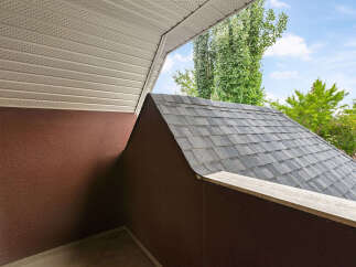 Discover the architectural details of this property, featuring a classic asphalt shingle roof that complements the textured brown exterior walls.