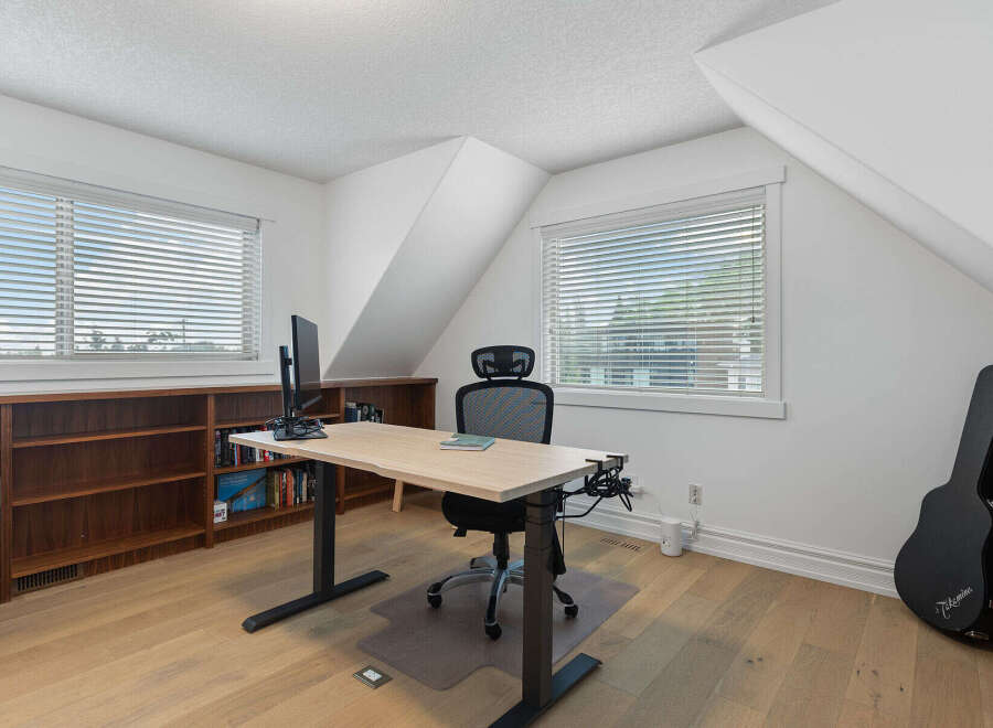 This home office features a spacious adjustable desk with a monitor, perfect for remote work or study.