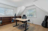 This home office features a spacious adjustable desk with a monitor, perfect for remote work or study.