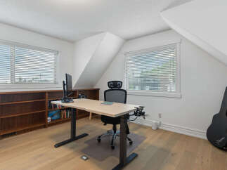 This home office features a spacious adjustable desk with a monitor, perfect for remote work or study.