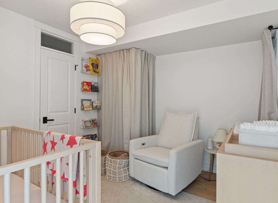 This charming nursery features a comfortable glider chair, a wooden crib with a playful star-patterned blanket, and a convenient changing table.