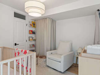 This charming nursery features a comfortable glider chair, a wooden crib with a playful star-patterned blanket, and a convenient changing table.