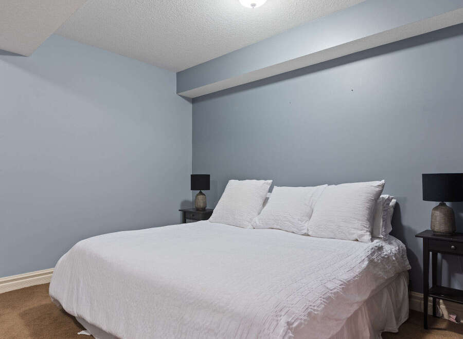 This inviting bedroom features a comfortable queen-size bed adorned with crisp white linens and plush pillows, creating a serene retreat.