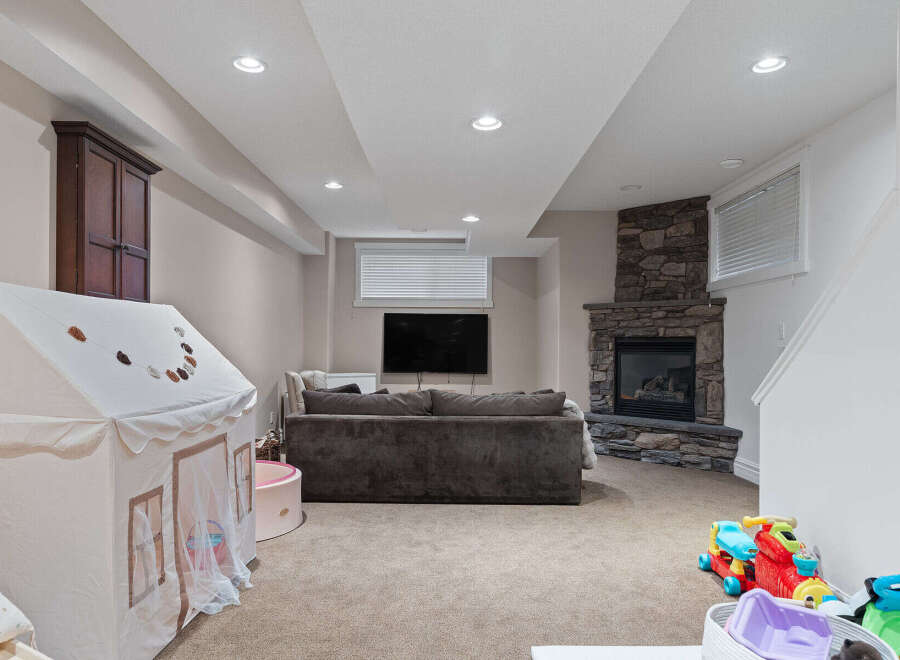 This finished basement offers a cozy family room with a stone fireplace and a mounted television, perfect for movie nights.