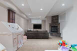 This finished basement offers a cozy family room with a stone fireplace and a mounted television, perfect for movie nights.