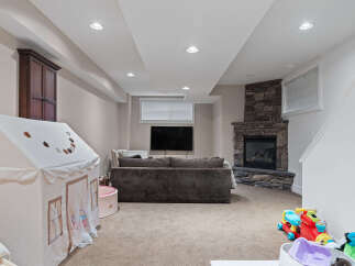 This finished basement offers a cozy family room with a stone fireplace and a mounted television, perfect for movie nights.
