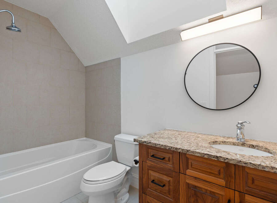 This modern bathroom features a sleek bathtub with a tiled accent wall and a convenient showerhead.